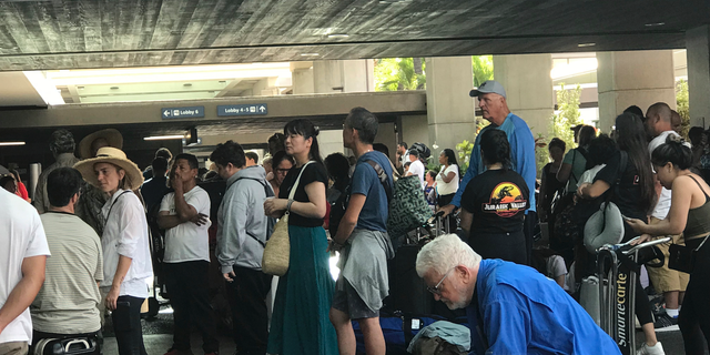 In this photo provided by Leslie Ryan, passengers jam the open air lobby at Terminal 2 at Daniel K. Inouye International Airport in Honolulu, Tuesday, June 18, 2019. Flights were being delayed and hundreds of people were waiting to go through security screening at Honolulu's airport after an active shooter scare. (Leslie Ryan via AP)