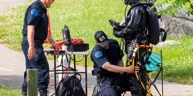 Police search the Kalamazoo River near Verburg Park, Tuesday, June 18, 2019, after finding the bodies of a mother and child inside a submerged vehicle, in Kalamazoo, Mich. Police believe a second child, who is missing, may also have been inside the vehicle when it entered the water late Monday evening. (Joel Bissell/Kalamazoo Gazette via AP)