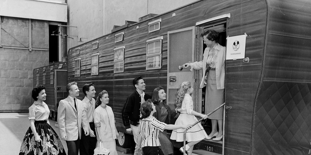 In this Aug 20, 1957, file photo, Walt Disney's Mouseketeers enter a large trailer that serves as their school on the Disney lot in Hollywood, Calif. Greeting them is their teacher Jean Seaman of the Los Angeles Public School System. Jimmy Dodd, red-haired and fortyish, is master of Mouseketeer ceremonies. Mouseketeer Annette Funicello can be seen at far left.