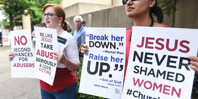 Jennifer Weed, left, and Nisha Virani, both of Birmingham, Ala., demonstrate outside Southern Baptist Convention's annual meeting Tuesday, June 11, 2019, during a rally in Birmingham, Ala. The For Such A Time As This protest calls for a change in the way the SBC views and treats women and demands action to combat sexual abuse within the establishment. (AP Photo/Julie Bennett)