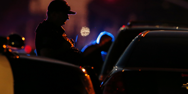 A law enforcement officer mans a barricade near a home that authorities have surrounded where an armed suspect has taken refuge after shooting a Sacramento police officer, Wednesday, June 19, 2019, in Sacramento, Calif. (AP Photo/Rich Pedroncelli)