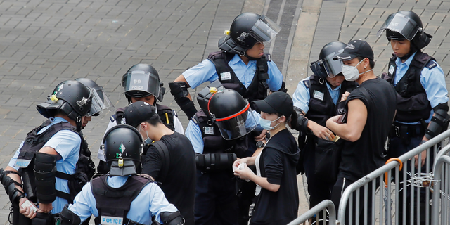 Riot police check the bags of protesters outside the Legislative Council in Hong Kong, Thursday, June 13, 2019. After days of silence, Chinese state media is characterizing the largely peaceful demonstrations in Hong Kong as a "riot" and accusing protesters of "violent acts." (AP Photo/Kin Cheung)