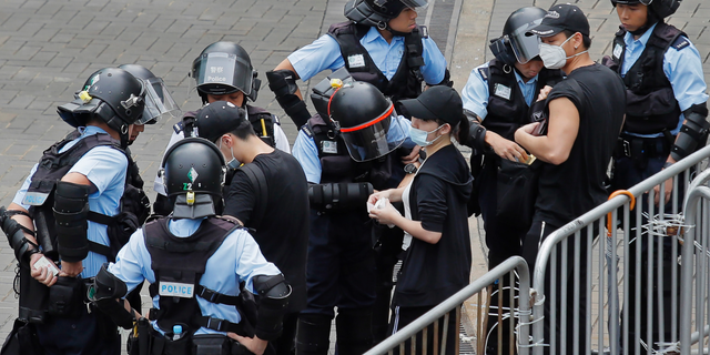 Riot police check the bags of protesters outside the Legislative Council in Hong Kong, Thursday, June 13, 2019. After days of silence, Chinese state media is characterizing the largely peaceful demonstrations in Hong Kong as a "riot" and accusing protesters of "violent acts." (AP Photo/Kin Cheung)