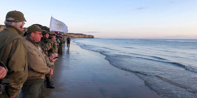 Re-enactors stand at the shore of Omaha Beach at sunrise as part of events to mark the 75th anniversary of D-Day on Omaha Beach in Vierville-sur-Mer, Normandy, France, Thursday, June 6, 2019. (Cedric Lecoz via AP)