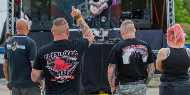 Three men and a woman watch a stage at the Shield and Sword Festival. (Photo by Daniel Schäfer/picture alliance via Getty Images)