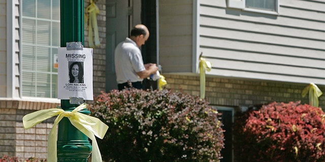 A relative works on a screen door of the ribbon-adorned house of Thelma Soares, mother of Lori Hacking, as a poster of her missing daughter hangs on a light pole July 28, 2004, in Orem, Utah. (Photo by George Frey/Getty Images)
