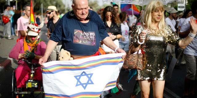 Participants hold flags during the annual Gay Pride parade in Jerusalem, Thursday, June 6, 2019. Thousands of people are marching through the streets of Jerusalem in the city's annual gay pride parade, a festival that exposes deep divisions between Israel's secular and Jewish ultra-Orthodox camps. (AP Photo/Ariel Schalit)