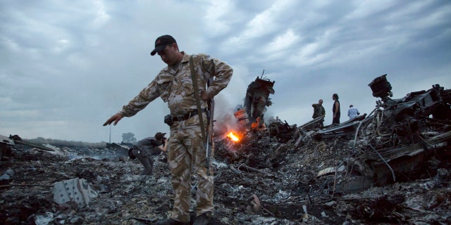 In this July 17, 2014 file photo, people walk amongst the debris at the crash site of a passenger plane near the village of Grabovo, Ukraine.