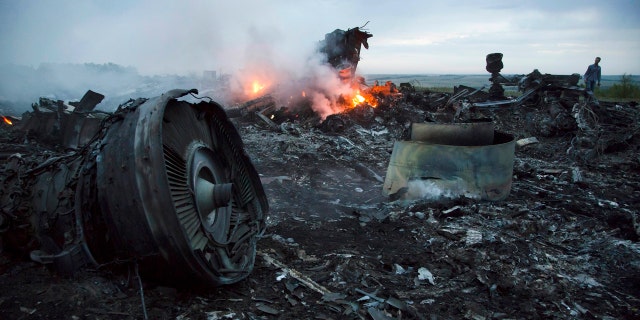 In this Thursday, July 17, 2014 file photo, a man walks amongst the debris at the crash site of a passenger plane near the village of Hrabove, Ukraine.