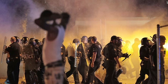 Police retreat under a cloud of tear gas as protesters disperse from the scene of a standoff after Frayser community residents took to the streets in anger against the shooting of a youth by U.S. Marshals earlier in the evening, Wednesday, June 12, 2019, in Memphis, Tenn. (Jim Weber/Daily Memphian via AP)