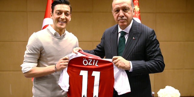 Turkish-German football player Mesut Ozil who plays for Arsenal (L) presents a jersey to Turkish President Recep Tayyip Erdogan before their meeting in London, United Kingdom on May 13, 2018. (Photo by Kayhan Ozer/Anadolu Agency/Getty Images)