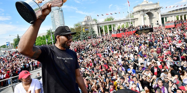 Toronto Raptors forward Kawhi Leonard holds his playoffs MVP trophy during the NBA basketball championship team's victory parade in Toronto, Monday, June 17, 2019. (Frank Gunn/The Canadian Press via AP)