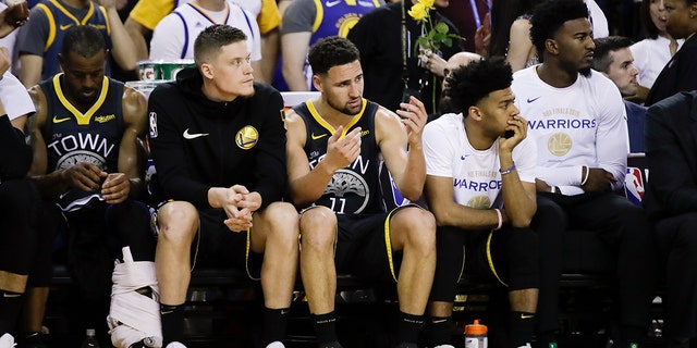 Golden State Warriors' Andre Iguodala, from left, sits on the bench with Jonas Jerebko, Klay Thompson, Quinn Cook and Jordan Bell during the second half of Game 4 of basketball's NBA Finals against the Toronto Raptors in Oakland, Calif., Friday, June 7, 2019. (AP Photo/Ben Margot)