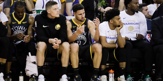 Golden State Warriors' Andre Iguodala, from left, sits on the bench with Jonas Jerebko, Klay Thompson, Quinn Cook and Jordan Bell during the second half of Game 4 of basketball's NBA Finals against the Toronto Raptors in Oakland, Calif., Friday, June 7, 2019. (AP Photo/Ben Margot)