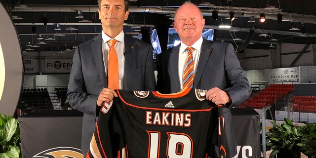 Anaheim Ducks head coach Dallas Eakins, left, and general manager Bob Murray pose with a jersey at Great Park Ice in Irvine, Calif., Monday, June 17, 2019. Eakins was hired as the Ducks' head coach on Monday, moving up from their AHL affiliate to take over a longtime NHL power that stumbled last season. (AP Photo/Greg Beacham)
