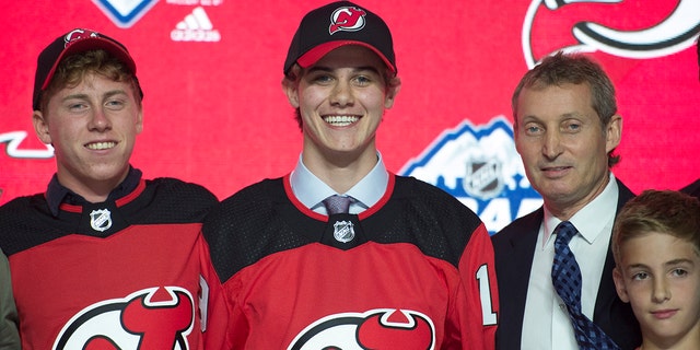 Jack Hughes, center, poses for photos after being selected by the New Jersey Devils with the first pick in the NHL hockey draft in Vancouver, British Columbia, Friday, June, 21, 2019. (Jonathan Hayward/The Canadian Press via AP)