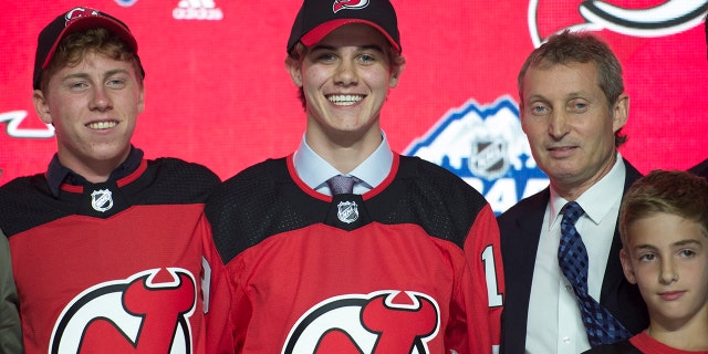 Jack Hughes, center, poses for photos after being selected by the New Jersey Devils with the first pick in the NHL hockey draft in Vancouver, British Columbia, Friday, June, 21, 2019. (Jonathan Hayward/The Canadian Press via AP)