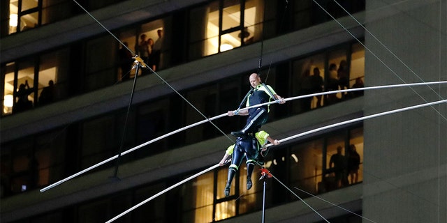 Aerialists Nik Wallenda, top, stepping over his sister Lijana as they walked on the high wire above Times Square on Sunday. (AP Photo/Jason Szenes)