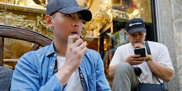 In this Monday, June 17, 2019, photo, Joshua Ni, 24, and Fritz Ramirez, 23, vape from electronic cigarettes in San Francisco.