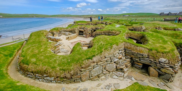 Tourists visiting Skara Brae, a Neolithic settlement located in the Mainland Orkney. In this prehistoric village, one of the best preserved groups of prehistoric houses in Western Europe, people can see the way of life of 5,000 years ago, before Stonehenge was built. (Credit: iStock)