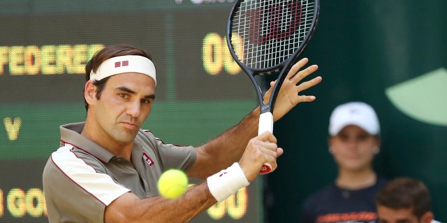 Swiss Roger Federer hits a backhand in the tennis ATP final against Belgium David Goffin in Halle, Germany, Sunday, June 23, 2019. (Friso Gentsch/dpa via AP)