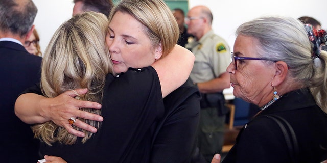 May Robson gets a hug from Kelly Cook, left, with Lee Cook, right, after William Talbott II was found guilty, Friday, in the 1987 killings of Jay Cook and Tanya Van Cuylenborg, a young Canadian couple. (Kevin Clark/The Herald via AP, Pool)