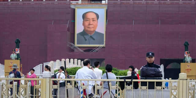A policeman stands guard near anti-riot gear and fire extinguishers in front of Mao Zedong's portrait on Tiananmen Gate on the 30th anniversary of a bloody crackdown of pro-democracy protestors in Beijing, Tuesday, June 4, 2019.