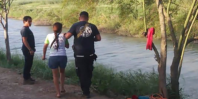 Tania Vanessa Ávalos of El Salvador, center left, is assisted by Mexican authorities after her husband and nearly two-year-old daughter were swept away by the current while trying to cross the Rio Grande to Brownsville, Texas, in Matamoros, Mexico, on Sunday. (AP)