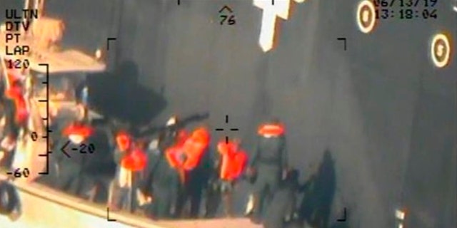This image released by the U.S. Department of Defense on Monday, June 17, 2019, and taken from a U.S. Navy helicopter, shows what the Navy says are members of the Islamic Revolutionary Guard Corps Navy removing an unexploded limpet mine from the M/T Kokuka Courageous. (U.S. Department of Defense via AP)