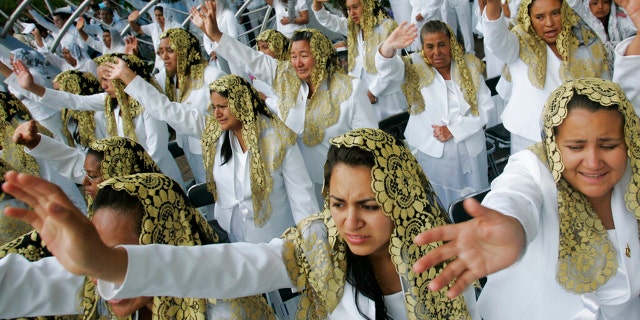 In this Aug. 14, 2009 file photo, worshippers raise their hands at "La Luz Del Mundo," or Light of the World church during a Holy Dinner celebration, one of the church's principal religious events, at the Hermosa Provincia Temple in Guadalajara, Mexico.(AP Photo/Carlos Jasso, File)