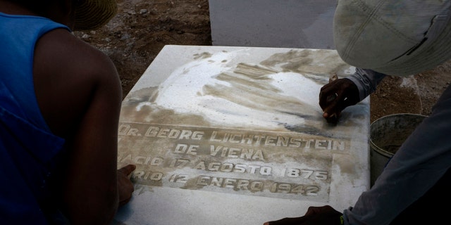 Workers clean the top of a tomb at the Jewish cemetery in Guanabacoa, eastern Havana, Cuba, June 12, 2019. Across the city, streets are being paved, monuments are being polished and historic sites are being restored. (AP Photo/Ramon Espinosa)