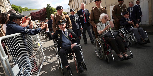 A spectator shakes the hand of a British veteran who is part of a procession leaving the Bayeux Cathedral after a ceremony to mark the 75th anniversary of D-Day in Bayeux, Normandy, on Thursday. (AP)