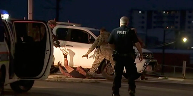 In this image made from video, police proceed to apprehend a suspect on the ground next to a white truck, Tuesday, June 4, 2019, in Darwin Australia.