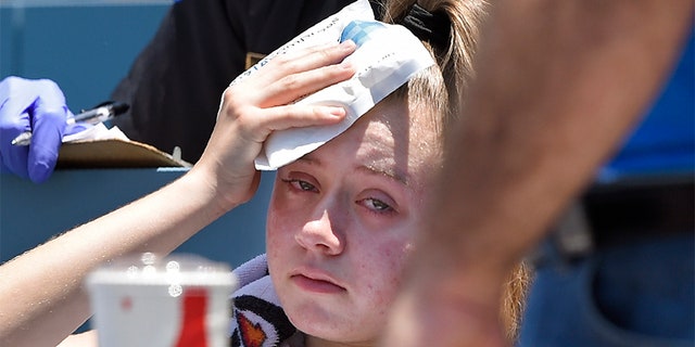 A young fan holds ice to her head after being hit with a foul ball hit by Los Angeles Dodgers' Cody Bellinger during the first inning of a baseball game against the Colorado Rockies on Sunday.