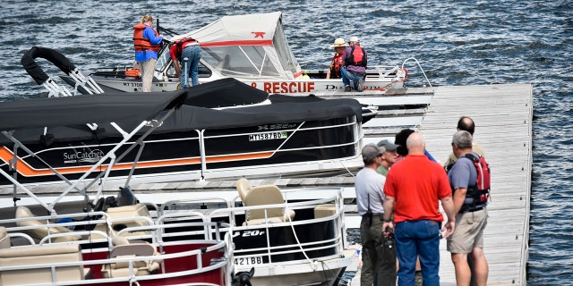 In this Monday, June 17, 2019 photo, emergency responders stage at the Yacht Basin marina east of Helena, Mont., as search and rescue teams search for a missing diver near Cemetery Island on Canyon Ferry Lake.
