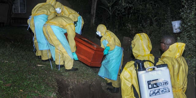 Workers wearing protective clothing bury Agnes Mbambu who died of Ebola, the 50-year-old grandmother of the 5-year-old boy who became Ebola's first cross-border victim, in the village of Karambi, near the border with Congo, in western Uganda Thursday, June 13, 2019. (AP Photo/Ronald Kabuubi)