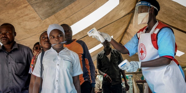People coming from Congo have their temperature measured to screen for symptoms of Ebola, at the Mpondwe border crossing with Congo, in western Uganda Friday, June 14, 2019. (AP Photo/Ronald Kabuubi)