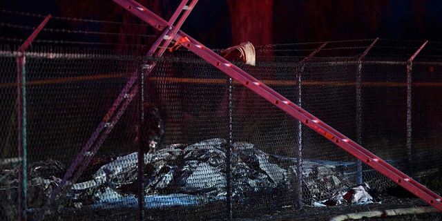 Remnants of an aircraft carrying nine people lies on the ground near a fence that surrounds Dillingham Airfield in Mokuleia, just off Farrington Highway, Friday, June 21, 2019. (Associated Press)