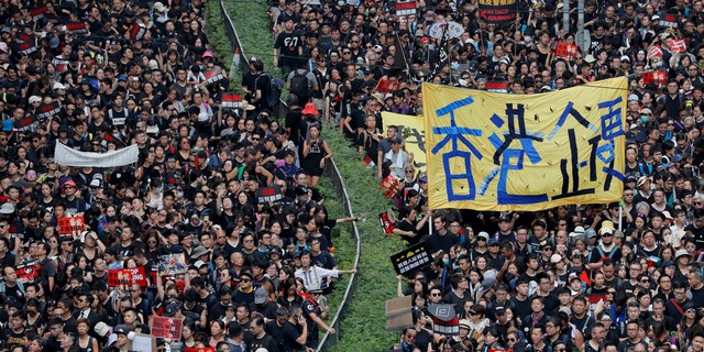 Tens of thousands of protesters march through the streets with a banner reading "Hong Kong stand firm" as they continue to protest an extradition bill, Sunday, June 16, 2019, in Hong Kong.