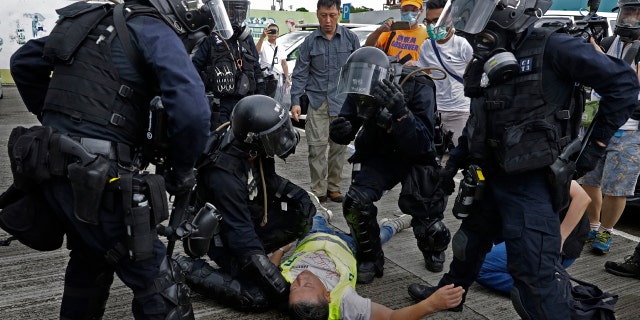 In this file photo taken Wednesday, June 12, 2019, a cameraman lies injured after riot police fire tear gas on protesters outside the Legislative Council in Hong Kong.