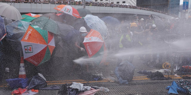 Protesters are hit by police water cannon during a demonstration against a proposed extradition bill in Hong Kong, China, using only their umbrellas as protection