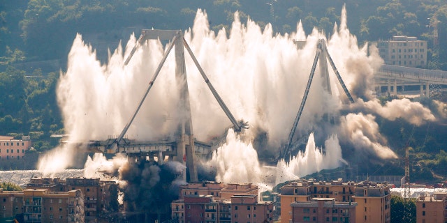 A cloud of dust rises as the remaining spans of the Morandi bridge are demolished in a planned explosion, in Genoa, Italy, Friday, June 28, 2019. (AP Photo/Antonio Calanni)