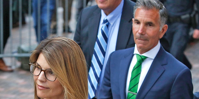 Lori Loughlin's Mossimo Giannulli, right, walks behind her outside the John Joseph Moakley United States Courthouse in Boston on April 3, 2019. Giannulli, 57, recently asked a federal court to allow him to serve the remainder of his five-year prison sentence. months to serve.  of the house.
