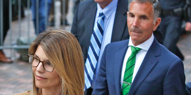 Lori Loughlin's Mossimo Giannulli, right, trails behind her outside of the John Joseph Moakley United States Courthouse in Boston on April 3, 2019. Giannulli, 57, recently asked a federal court to allow him to serve the remainder of his five-month prison sentence from home.