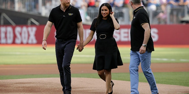 Britain's Prince Harry, left, and Meghan, Duchess of Sussex, walk off the field.