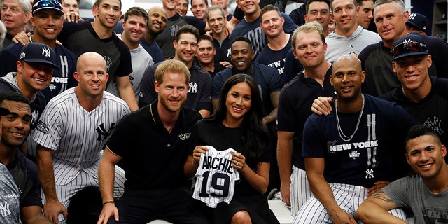 Britain's Prince Harry and Meghan, Duchess of Sussex pose for a picture with players of the New York Yankees.