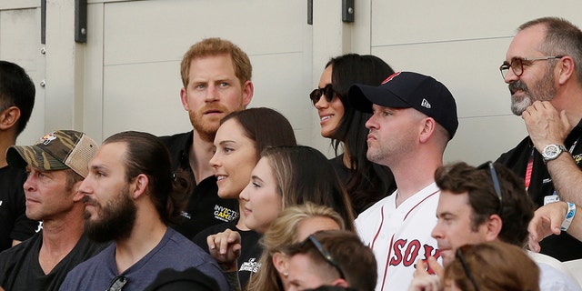 Britain's Prince Harry, top left, and Meghan, Duchess of Sussex, watch during the first inning of a baseball game.