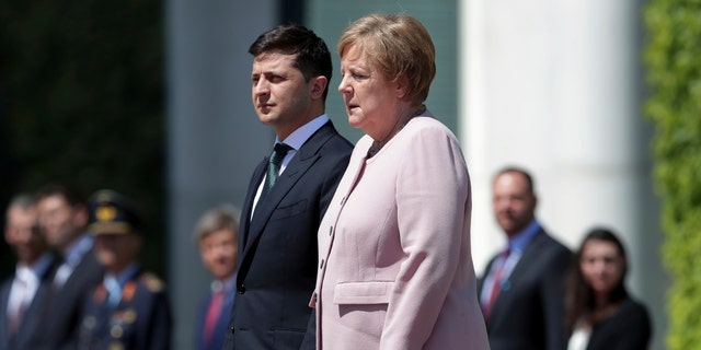 German Chancellor Angela Merkel, right, trembles strong as she and Ukraine's President Volodymyr Zelenskiy, left, attend the national anthems as part of a military welcome ceremony in Berlin, Germany. AP Photo/Michael Sohn