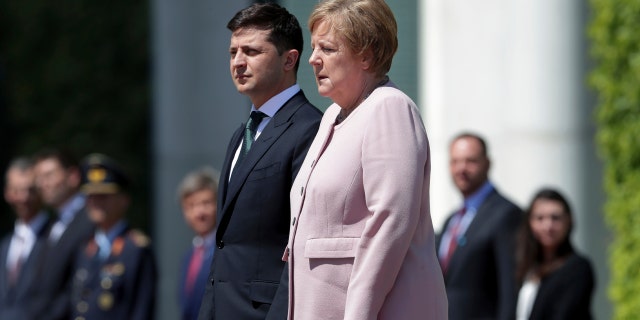 German Chancellor Angela Merkel, right, trembles strong as she and Ukraine's President Volodymyr Zelenskiy, left, attend the national anthems as part of a military welcome ceremony in Berlin, Germany. AP Photo/Michael Sohn