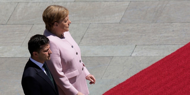 German Chancellor Angela Merkel, right, and Ukrainian President Volodymyr Zelenskiy, left, listen to the national anthems during the welcoming ceremony, prior to a meeting at the chancellery in Berlin, Germany, Tuesday, June 18, 2019.